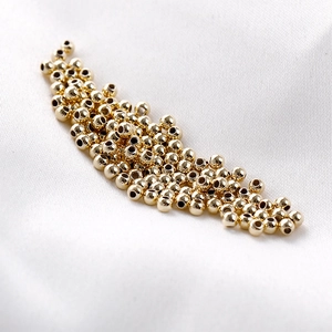 Polished 14K gold filled round spacer beads for DIY jewelry making on white silk