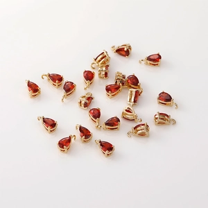 Detalle de colgantes de gota de circón rojo oscuro con engaste chapado en oro de 14K