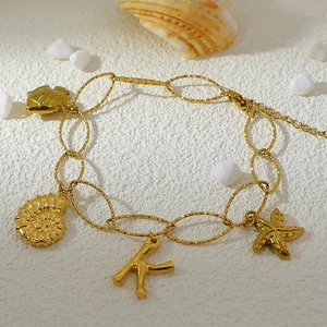 Detail of 18K gold plated anklet featuring marine charms like starfish and a K pendant