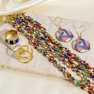 Detail view of colorful enamel jewelry set with 18k gold plating on marble surface