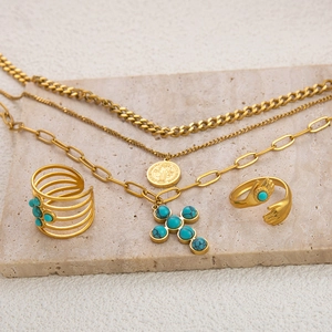 Detail eines Gold-Schmucksets mit Türkis-Akzenten auf einer Steinplatte