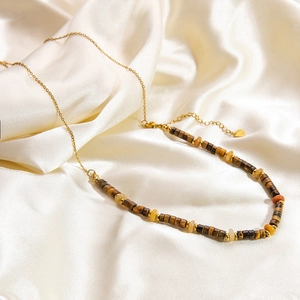 Détail d'un collier en titane doré 18K avec perles œil de tigre sur soie blanche douce
