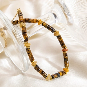Détail de bracelet perlé avec pierres œil de tigre et touches dorées sur verre
