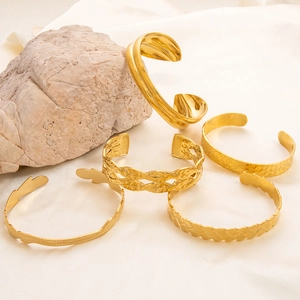 Dettaglio di cinque bracciali a C placcati in oro con finiture martellate e superfici testurizzate