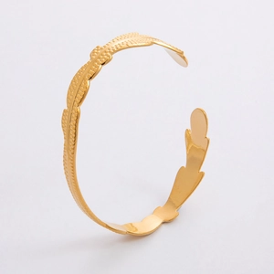 Dettaglio del bracciale a fascia dorato a forma di C con trama a foglia realistica