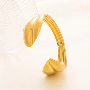 Dettaglio del bracciale dorato a forma di foglia con finitura martellata irregolare