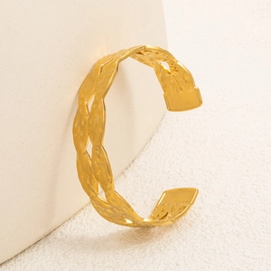 Dettaglio macro del bracciale rigido oro opaco con trama a martello e intreccio