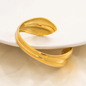 Elegante bracciale rigido aperto dorato con motivo a foglia martellata e design sobrio