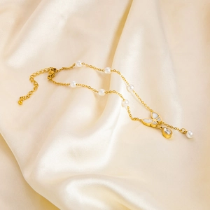 Detail der goldenen Fußkette mit Perlen, Schmetterlingsanhänger und Zirkonanhänger