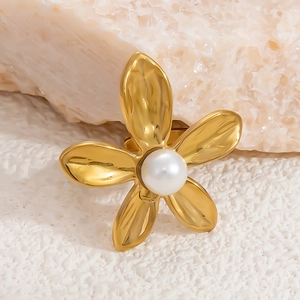 Macro-opname van 18K gouden bloemenoorbel met gehamerde textuur en een witte parel