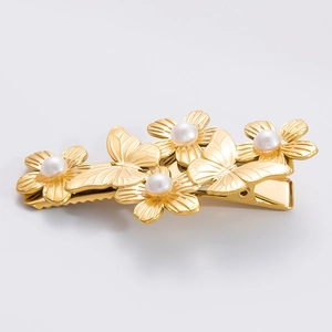 Eleganter goldener Haarclip mit Schmetterlingsblumen und Perlen auf grauem Hintergrund