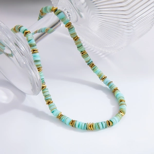 Collier perlé bohème avec disques vert menthe et triangles dorés sur flacon en verre