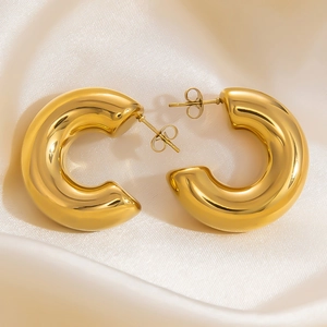 Close-up of chunky gold-plated C-shaped hoop earrings with a polished mirror finish