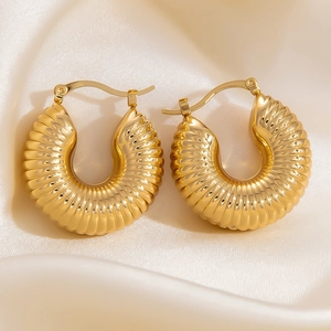 Macro shot of 18k gold plated chunky croissant hoop earrings on white silk fabric