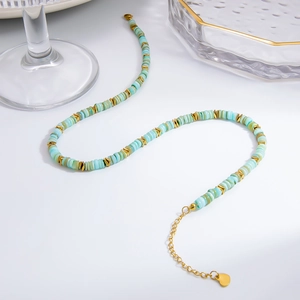 Détail de perles en coquille bleue et flèches dorées sur un collier en acier inoxydable