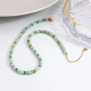 Détail du collier de perles turquoise avec intercalaires triangles dorés et breloque cœur