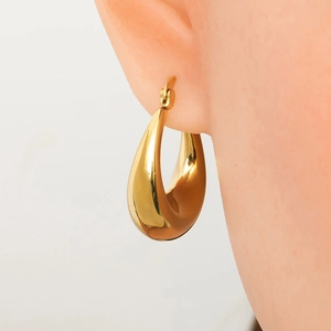Close-up of chunky gold-plated stainless steel teardrop hoop earring on model ear