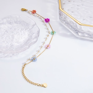Detail einer zweilagigen Edelstahl-Goldkette mit Perlen und bunten Blumenmotiven