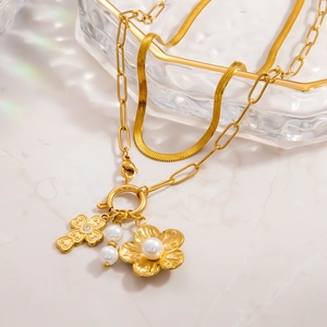 Détail du collier double rang en or 18k avec pendentifs fleur, croix et perles