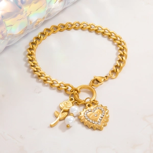 Détail de la chaîne en acier doré 18k avec breloques rose, perle et cœur œil