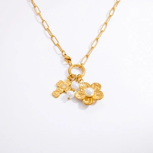 Gros plan du pendentif croix florale dorée avec perles sur une chaîne en or 18 carats