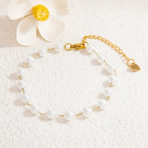 Détail du bracelet en perles avec chaîne dorée et pendentif cœur