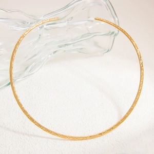 Detail of 18k gold stainless steel choker featuring a handcrafted hammered metal texture