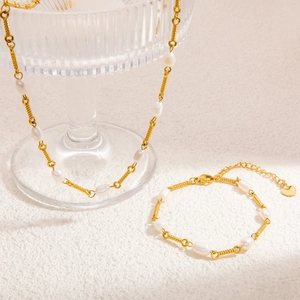 Detailaufnahme von 18K vergoldeter Perlenkette und Armband mit spiralförmigen Gliedern