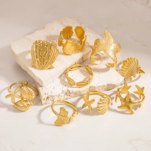Dettaglio di anelli placcati oro a tema marino con forme di conchiglie e stelle marine