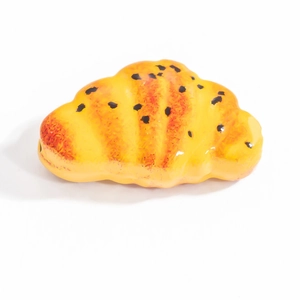 Macro detail of high-shine resin croissant pendant with realistic golden-brown baking texture