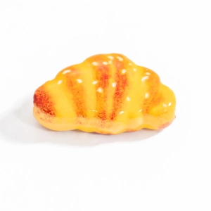 Macro detail of a 3D croissant shaped stainless steel pendant with glossy yellow finish