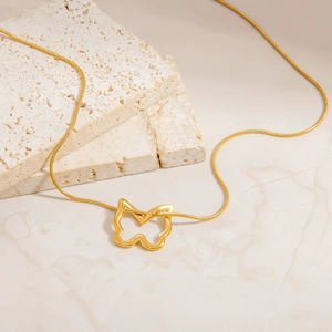 Detailansicht einer goldenen Schmetterlingskette auf Schlangenkette auf Marmor und Stein