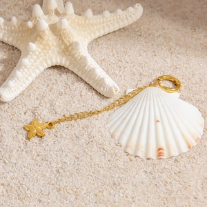 Detailed view of starfish pendant and gold clasp on sand with nautical decorations