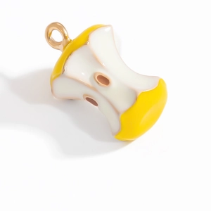 Détail macro d'un pendentif trognon de pomme jaune avec émail et anneau doré