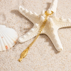 Golden sea life necklace with fish pendant on sand beach with starfish and shells