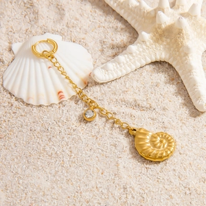 Detail of 18K gold-plated starfish shell pendant with zircon chain on white sand beach
