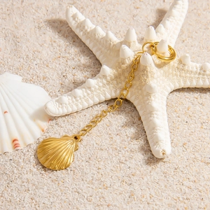 Detail of 18K gold plated seashell pendant on sand with starfish for beach aesthetic
