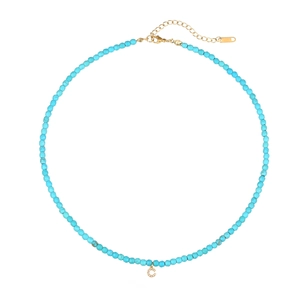 Dettaglio macro della collana di perle celesti con ciondolo a lettera C dorato
