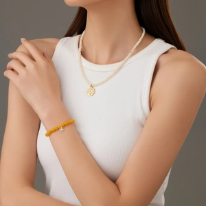 Elegante witte kralenketting met gouden zonnehanger en gele klaverblad armband