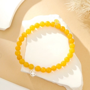 Detailopname van gele kralenketting met smiley en klaver hanger op een stenen basis