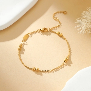 Close-up of gold beaded cross chain with lobster clasp and adjustable extension link