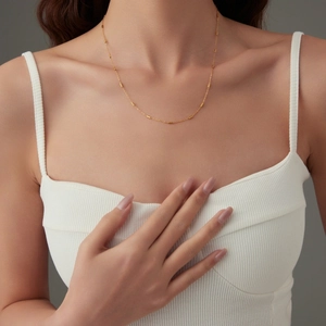Elegant gold choker necklace with bead and tube accents on a female model