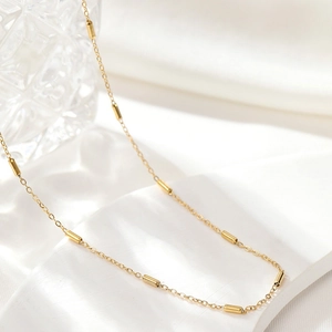 Detailed view of luxury gold bead chain necklace with polished cylindrical accents