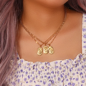 Nahaufnahme eines Models mit ovalen Sternzeichen-Halsketten aus Gold mit Zirkon-Inlay