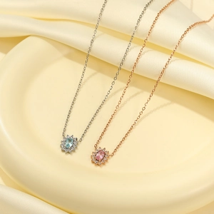 Dettaglio di collane girasole in argento e oro rosa con zirconi su seta color crema