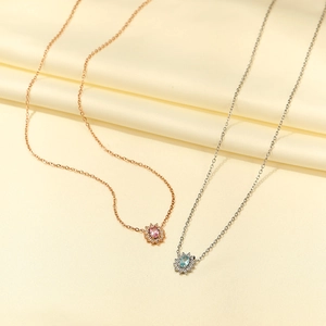 Dettaglio di collane in oro rosa e argento con pendenti in zircone su seta gialla