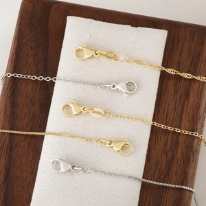 DIY gold and silver plated box and link necklace chains with lobster clasps on a wood tray