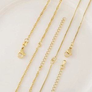 Gold plated brass jewelry chains with lobster clasps and extenders in a ceramic tray