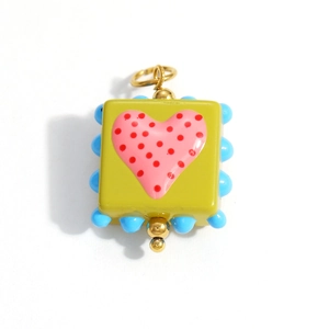 Macro shot of square yellow glass heart pendant with colorful beads and gold loop