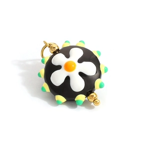 Macro shot of a black heart glass pendant with white daisy and colorful cone details